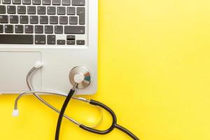 Stethoscope keyboard laptop computer isolated on yellow background. Modern medical Information technology and sofware advances concept. Computer and gadget diagnostics and repair
