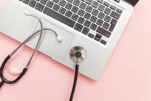 Stethoscope keyboard laptop computer isolated on pink background. Modern medical Information technology and sofware advances concept. Computer and gadget diagnostics and repair photo