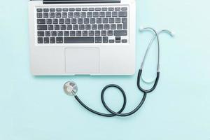 Stethoscope keyboard laptop computer isolated on blue background. Modern medical Information technology and sofware advances concept. Computer and gadget diagnostics and repair photo