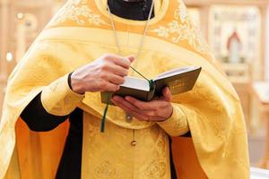 Iglesia Ortodoxa. cristiandad. manos de sacerdote sosteniendo el libro sagrado de la biblia en el fondo tradicional de la iglesia ortodoxa el día de la boda, la víspera de pascua o la celebración de navidad. religión fe orar símbolo foto