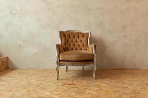 Beautiful luxury classic biege clean interior room in grunge style with brown baroque armchair. Vintage antique brown-gray chair standing beside wall. Minimalist home design. photo