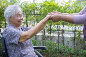 Holding hands Asian senior or elderly old lady woman patient with love, care, encourage and empathy at park. photo