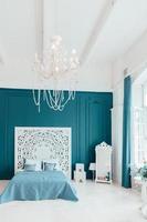 Beautiful luxury classic clean interior bedroom in white and deep blue color with king-size bed and chic carved furniture. Bright modern stylish interior bedroom and living room in minimalist style. photo