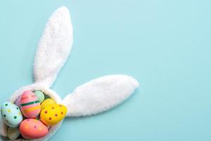 Felices Pascuas. huevos pintados de pascua de colores en orejas de conejo blanco con espacio de copia foto