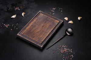 Black metal spoon and rectangular cutting board on black concrete background photo