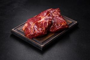 Raw organic marbled beef steaks with spices on a wooden cutting board photo