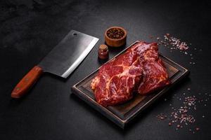 Raw organic marbled beef steaks with spices on a wooden cutting board photo