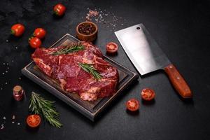 Raw organic marbled beef steaks with spices on a wooden cutting board photo