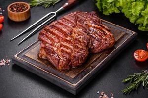 Grilled ribeye beef steak, herbs and spices on a dark table photo