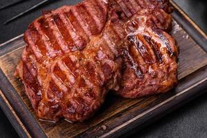 Grilled ribeye beef steak, herbs and spices on a dark table photo