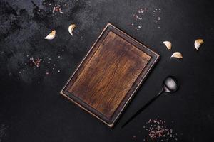 Black metal spoon and rectangular cutting board on black concrete background photo