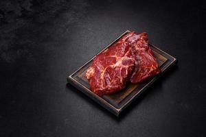 Raw organic marbled beef steaks with spices on a wooden cutting board photo