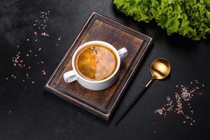 Chicken noodle soup with parsley and vegetables in a white plate photo