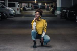una mujer negra milenaria pensativa vestida de moda en un estacionamiento subterráneo