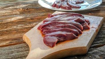 Raw pork liver on cutting board on rustic wooden table photo