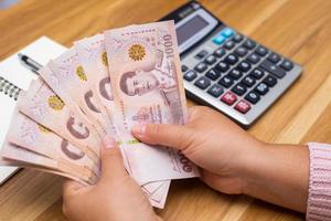 Close up of asian woman with calculator counting money.Woman calculate the spending at home. photo