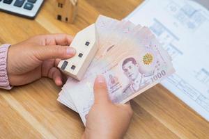 Cerca de la mujer asiática con calculadora contando dinero. Mujer calcular el gasto en casa. foto