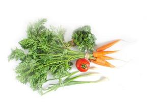 zanahoria fresca con hojas verdes, tomate, cebolla y perejil sobre fondo blanco. foto