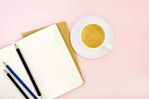Two writing pads, pencils and a white porcelain cup with coffee
