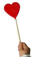 Child's hand holding an heart shaped lollipop, with copyspace photo