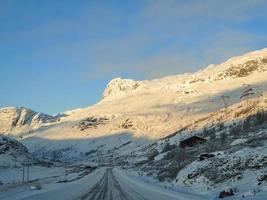 conduciendo al amanecer dorado a través de montañas y pueblos en noruega. foto