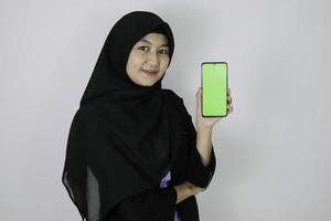 Happy asian islamic business women pointing and show blank screen on phone. photo