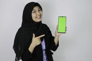 Happy asian islamic business women pointing and show blank screen on phone. photo