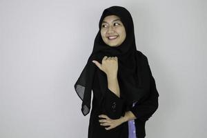 Smiling Young Asian Islam woman wearing headscarf is smile and pointing behind. photo