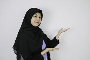 Happy Young Asian Islam woman wearing headscarf is smile and pointing beside. photo