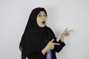 Shock Young Asian Islam woman wearing headscarf is smile and pointing beside. photo