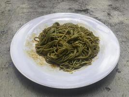 Spicy green noodles in white plate photo