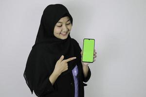mujeres de negocios islámicas asiáticas felices señalando y mostrando una pantalla en blanco en el teléfono. foto