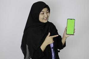 Happy asian islamic business women pointing and show blank screen on phone. photo