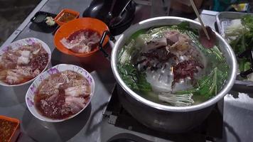gegrilltes schweinefleisch ein beliebtes partyessen in thailand, schweinefleisch und andere fleischsorten werden auf einer pfanne gegrillt und zum essen in dip-saucen getaucht. video