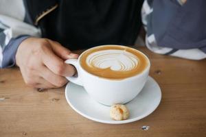 top view of a cup of late coffee with heart shape design on top on cafe table photo