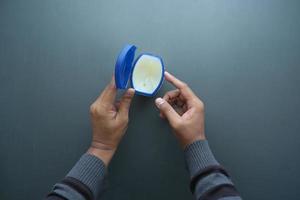 top view of man hand using petroleum jelly on black background photo