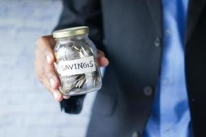 young man saving coins in a jar white sited photo