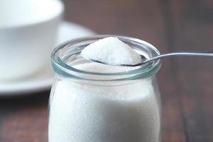 white sugar and spoon in a container on black background, photo