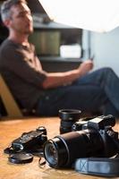 cámara y equipo sobre la mesa en el estudio en el fondo del fotógrafo sentado foto