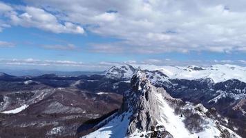 vista aérea do drone do pico da montanha de difícil acesso para alpinistas durante um dia ensolarado de inverno. alpinismo e alpinistas. céu azul e cores vibrantes brancas. tiro cinematográfico. mais aventura na vida.