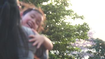 la pequeña hija corrió hacia su madre y la abrazó en el parque en otoño. un niño lindo se está divirtiendo con mamá en el patio de recreo video