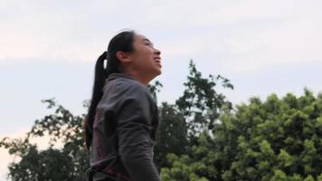 Aziatische vrouwelijke atleet met koptelefoon poseert met basketbal op het basketbalveld buiten. video