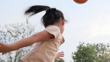 vrolijk schattig meisje dat buiten basketbal speelt. video
