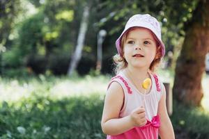 Funny child with candy lollipop, happy little girl eating big photo