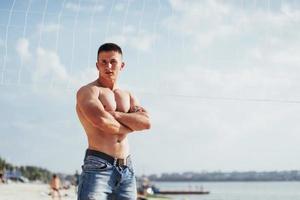 Beautiful athletic bodybuilder guy, carries out exercises with d photo