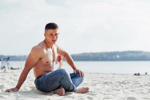 Beautiful athletic bodybuilder guy, carries out exercises with d photo