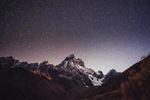 Fantastic starry sky. Autumn landscape and snow-capped peaks