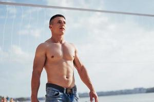 Beautiful athletic bodybuilder guy, carries out exercises with d photo