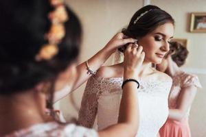 Wedding day. Beautiful bride trying on earrings photo