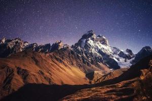 fantástico cielo estrellado. paisaje otoñal y picos nevados foto